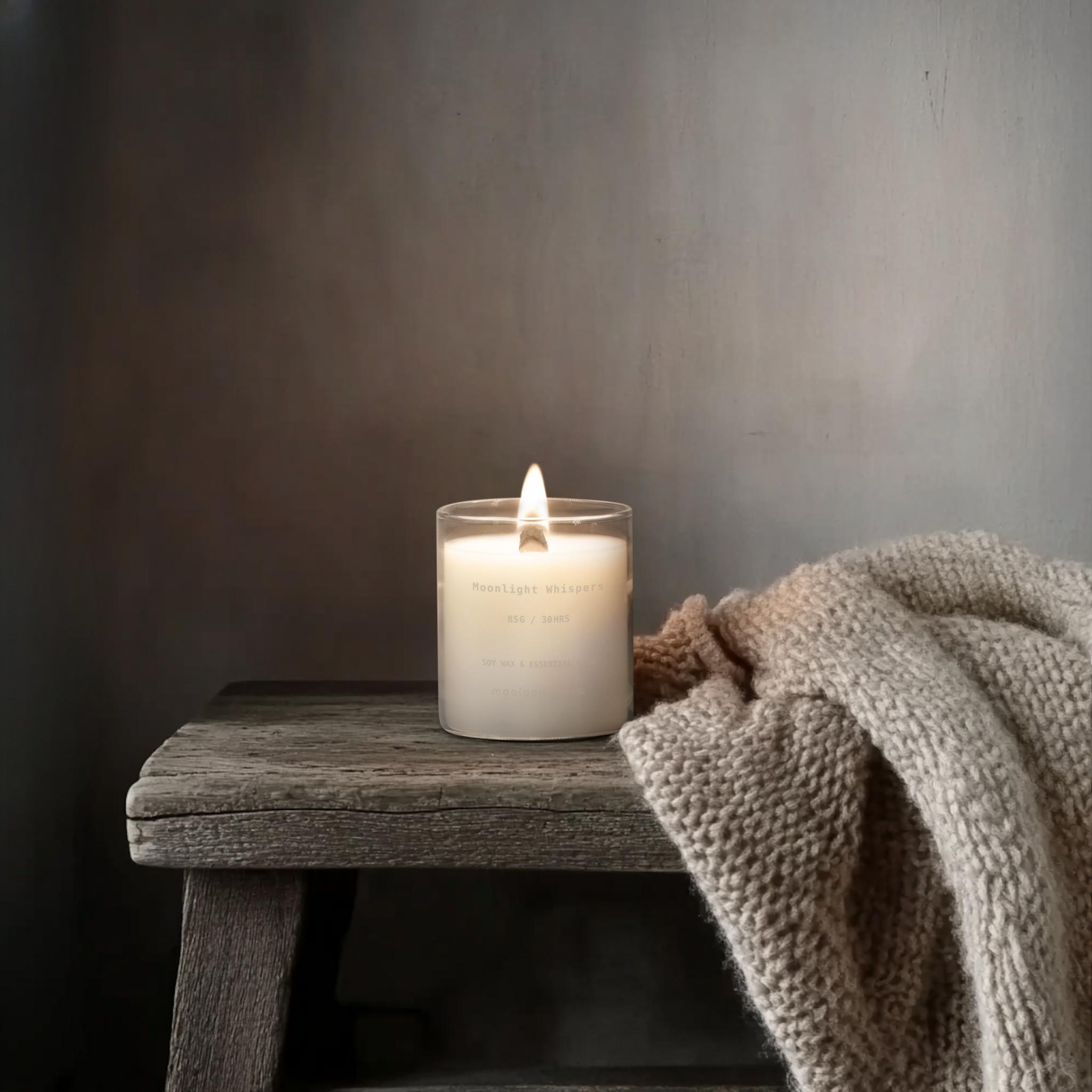 Moonlight Whispers candle glowing on a rustic bench with soft knit blanket – calming home fragrance decor